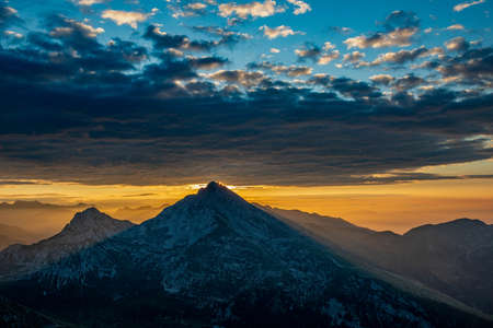 Sunrise in the mountains with the sun coloring the cloudsの写真素材