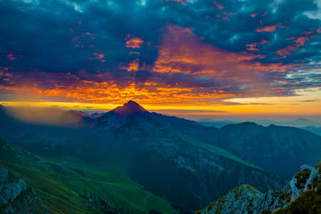 Sunrise in the mountains with the sun coloring the cloudsの写真素材