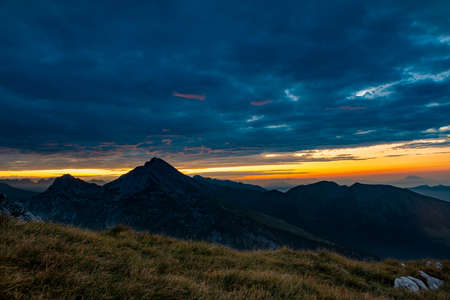 Sunrise in the mountains with the sun coloring the cloudsの写真素材