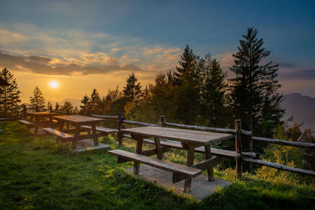 Tables with wooden benches in the mountains at sunsetの写真素材