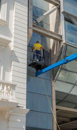Glass cleaner in the shopping center using the mobile platform to reach the upper parts of the...