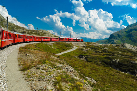 Sankt Moritz Switzerland May 13 2023: Little red train traveling in the Swiss mountains and connecting Switzerland with Italyの写真素材