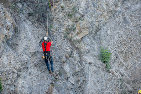 Dossena Italy August 24th 2023: Climber placing safety nets to avoid falling rocksのeditorial素材