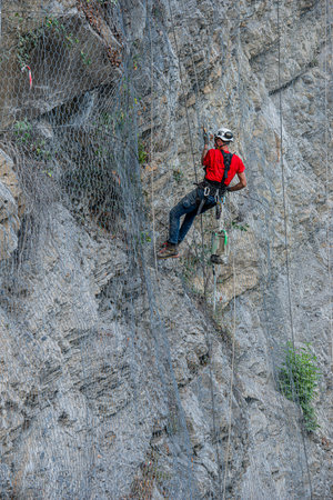 Dossena Italy August 24th 2023: Climber placing safety nets to avoid falling rocksのeditorial素材
