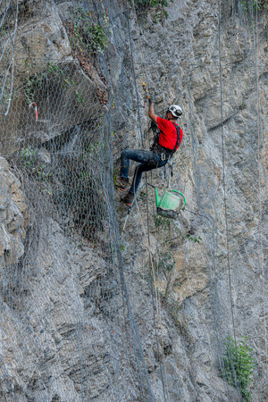 Dossena Italy August 24th 2023: Climber placing safety nets to avoid falling rocksのeditorial素材