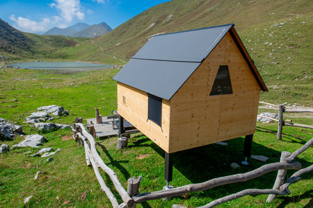 Wooden house on a green meadow with mountains in the backgroundの写真素材