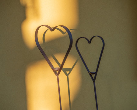 Metal heart reflecting the shadow against the wallの写真素材