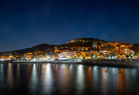 Pietra Ligure houses illuminated at night seen from the seaの写真素材
