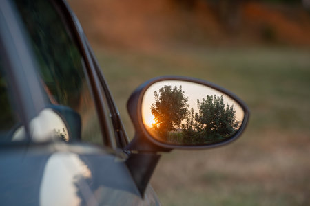 Car rearview mirror reflecting the setting sunの写真素材