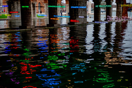 Venice Italy October 8, 2024: Venice International Art Biennale Colored LED lights reflecting the words We are all foreigners in the waterの写真素材