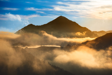 Fog enveloping the mountains at sunsetの写真素材