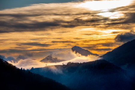 Fog enveloping the mountains at sunsetの写真素材