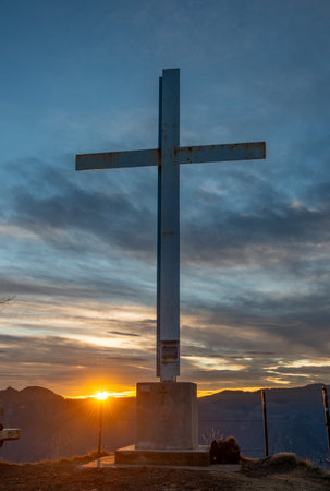 Iron cross on the mountain top at sunsetの写真素材