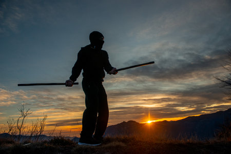 Training with poles at sunset on the top of the mountainの写真素材