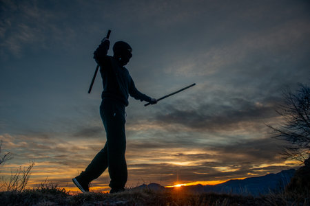 Training with poles at sunset on the top of the mountainの写真素材