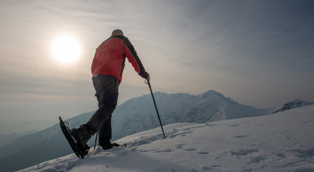 Mountain hiker walking with snowshoes after snowfallの写真素材