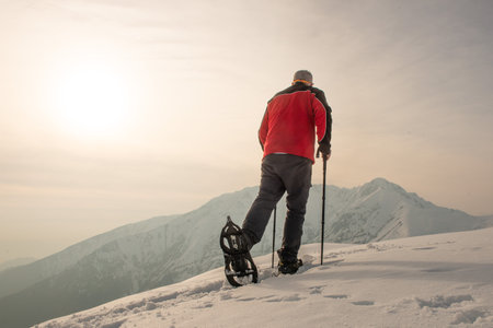 Mountain hiker walking with snowshoes after snowfallの写真素材