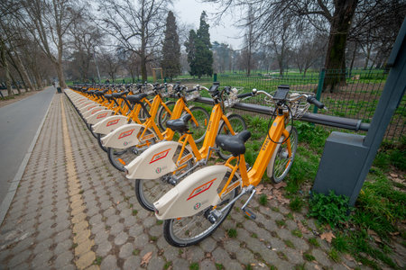 Milan, Italy, February 27, 2026: A row of yellow bikes from the bike-sharing service parked along a...