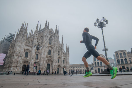 Milan, Italy, March 12, 2026: Athlete running in the Piazza del Duomo in Milan on a cloudy day, with...