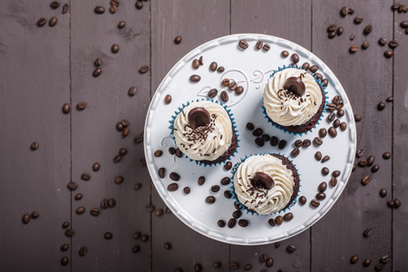 three cupcakes whit cream and coffee on the wood whit coffe beansの写真素材