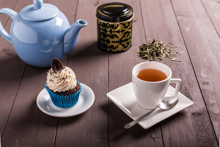 tea cup and cupcake whit chocolate and cream on the woodの写真素材