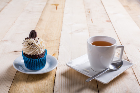 tea cup and cupcake whit chocolate and cream on the woodの写真素材