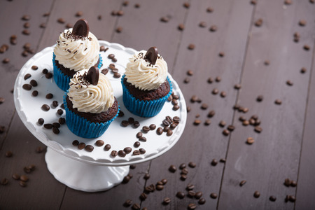three cupcakes whit cream and coffee on the wood whit coffe beansの写真素材