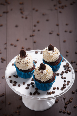 three cupcakes whit cream and coffee on the wood whit coffe beansの写真素材