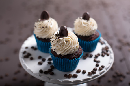 three cupcakes whit cream and coffee on the wood whit coffe beansの写真素材
