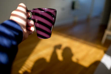 man with coffee mug in shadowの写真素材