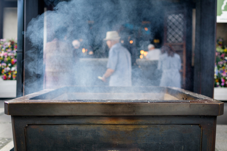 Osaka Shitennoji temple incense sticks and man in backgroundの写真素材