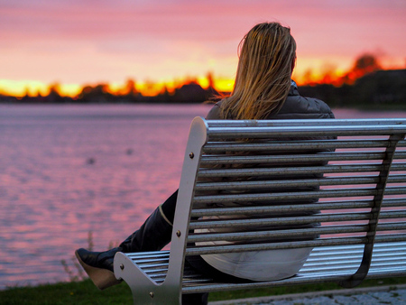 blonde girl on bench enjoying sunsetの写真素材
