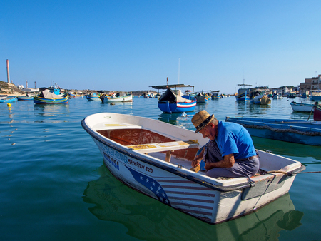 Marsaxlokk, Malta: October 08: Unidentified old man prepares fisher boat on October 08, 2014 in Marsaxlokk, Malta.のeditorial素材
