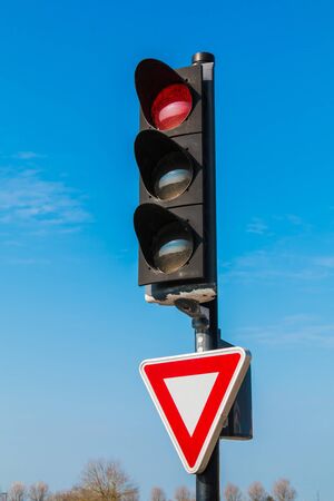 red traffic light with yield sign on blue skyの写真素材