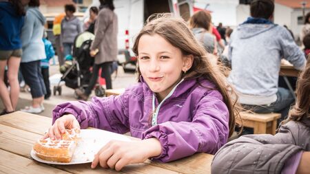 Bretignolles sur Mer, France - may 5, 2016 : a little girl eats a sugar waffle on the beachのeditorial素材