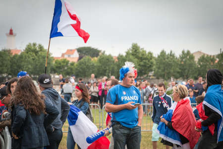 Saint Gilles Croix de Vie, France - July, 10, 2016 : In the fan zone of the city, supporters of Team France waiting for the match of the final of Euro 2016, France - Portugal waving French flags and being dressed in the colors of their countryのeditorial素材