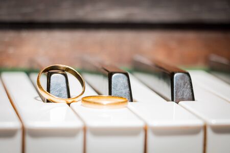 gold wedding rings on a piano keyの写真素材