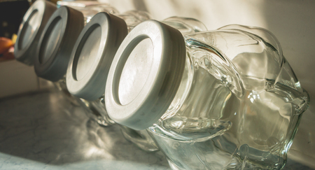 Four empty kitchen jars lined up on a worktopの写真素材