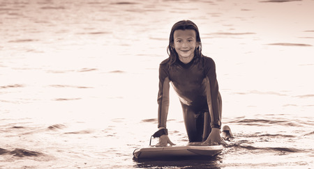 girl dressed with a wetsuit swimming in the ocean with a bodyboardの写真素材
