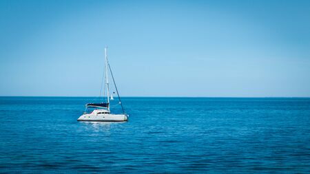 luxury boat anchored in the middle of a turquoise sea paradiseの写真素材