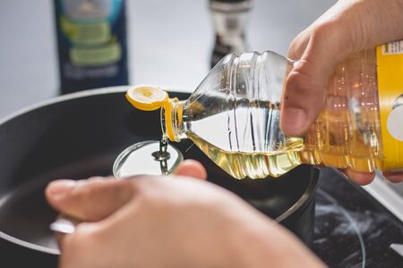 Cook pouring oil into a hot black saucepanの写真素材