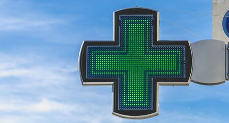 green cross of pharmacy electronics on blue skyの写真素材