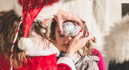 Bretignolles sur Mer, France - December 18, 2016 : During the Christmas period, a little girl is applying makeup in a stand on a Christmas marketのeditorial素材