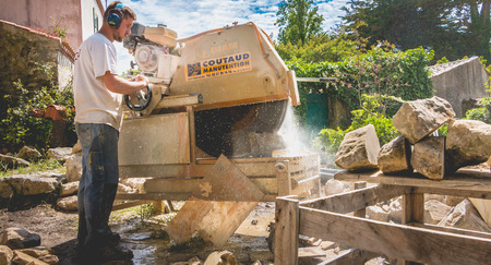 Noirmoutier, France - May 16, 2017 :  a man cutting a stone with a water saw on a renovation siteのeditorial素材