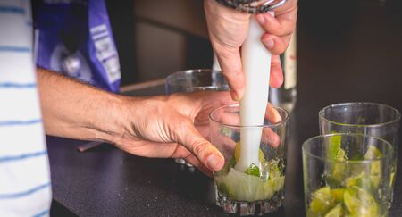 barman crushes green lemons with a pill to make caipirihnas bresillianの写真素材