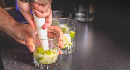 barman crushes green lemons with a pill to make caipirihnas bresillian
