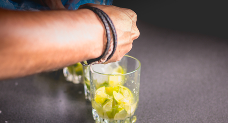 bartender puts ice cubes in glasses of brezillian caipirinha on an anthracite worktopの写真素材