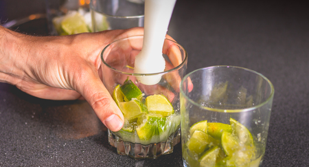barman crushes green lemons with a pill to make caipirihnas bresillianの写真素材