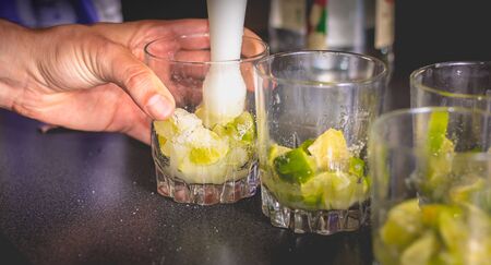 barman crushes green lemons with a pill to make caipirihnas bresillianの写真素材