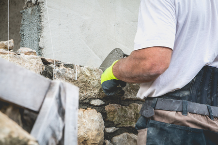 worker rides a stone wall on a traditional renovation site of NOIRMOUTIER, FRANCEの写真素材